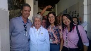 Foto horizontal de quatro pessoas sorridentes, olhando para a frente, em busto completo. Da esquerda para a direita, Antônio Santana, homem alto, veste camisa social azul e usa crachá do Senac. Ao seu lado, Doutora Maria Lígia, senhora de cabelos curtos e grisalhos, veste camisa e blazer brancos. Ao seu lado, Martha Luíza, cabelos castanhos ondulados, usa óculos, camisa estampada e crachá do Senac. E por último, Andréia Figueiredo, cabelos escuros e lisos, usa camisa rosa de botão e crachá do Senac.